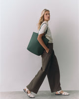 Person holding a tote bag, wearing a t-shirt, wide-leg pants, and sandals.