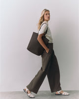 Person standing with a large shoulder bag wearing a casual outfit and open-toed sandals