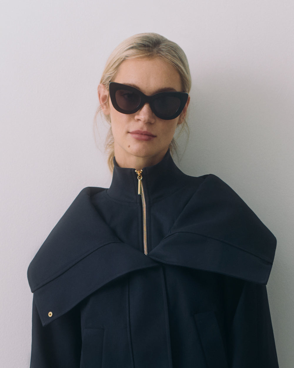 Woman wearing a cape and sunglasses.