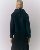 Person wearing a jacket with a wide collar, seen from the back.