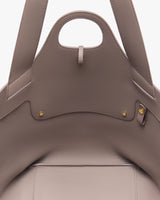 Close-up of an open handbag with two handles and gold button details.