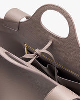 Close-up of an open handbag with a zipper and tied strap inside.