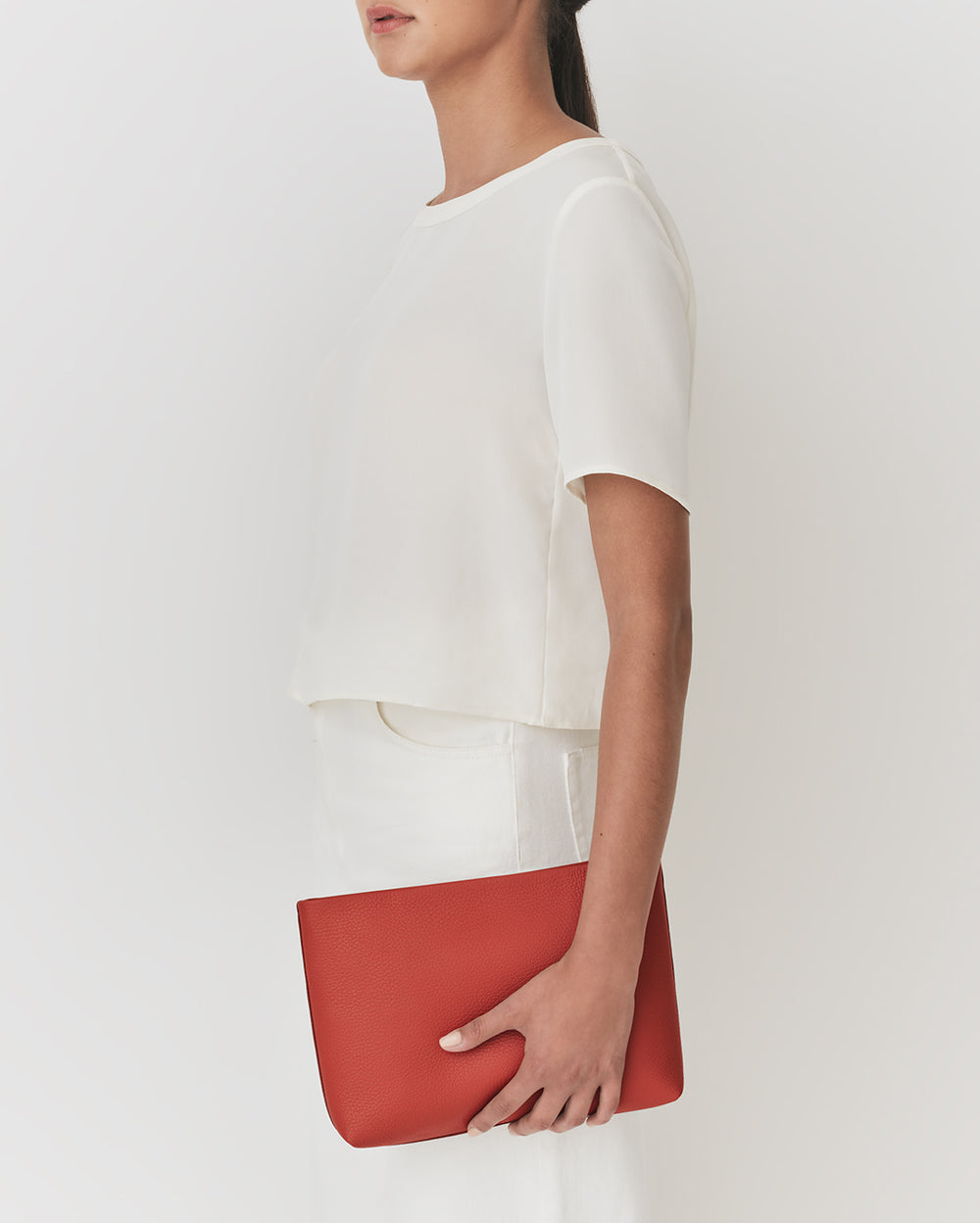 Person holding a pouch wearing a short-sleeve top and skirt facing left