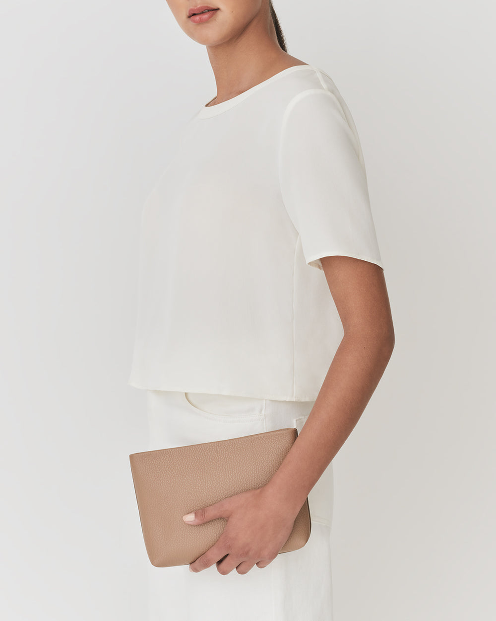 Model holding a clutch bag wearing a short-sleeve top and pants