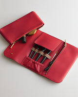 Makeup brushes in an open case with a zippered pocket and slots.