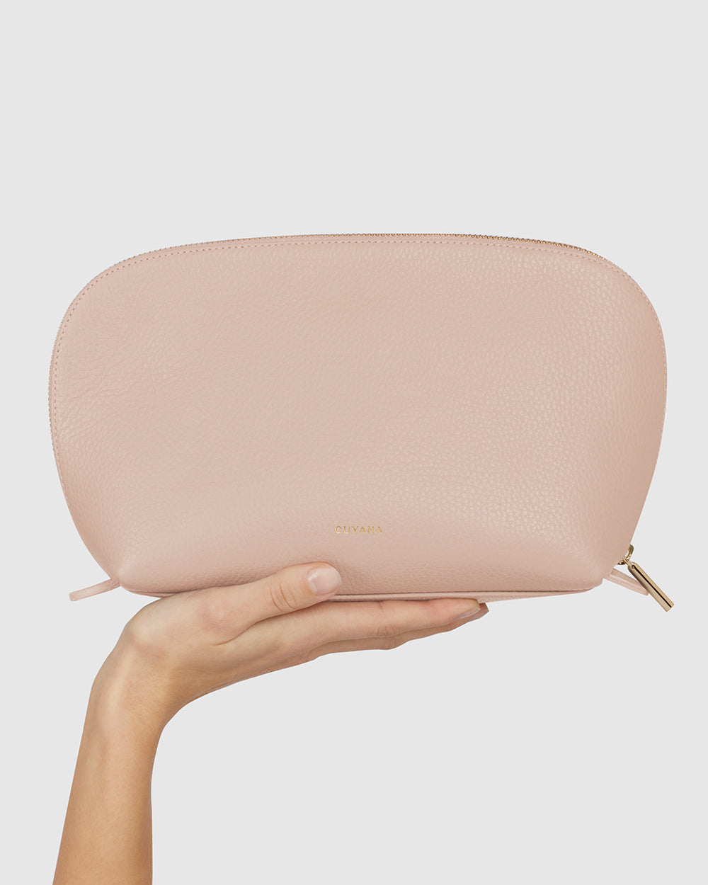 Hand holding a textured clutch purse with a zipper closure.
