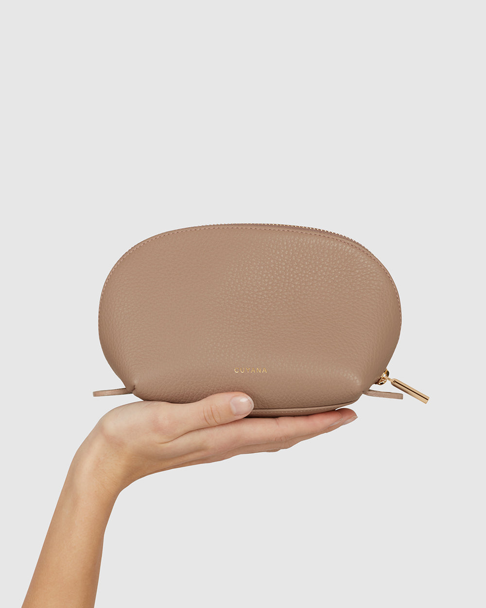 Hand holding a small zippered pouch against a plain background.