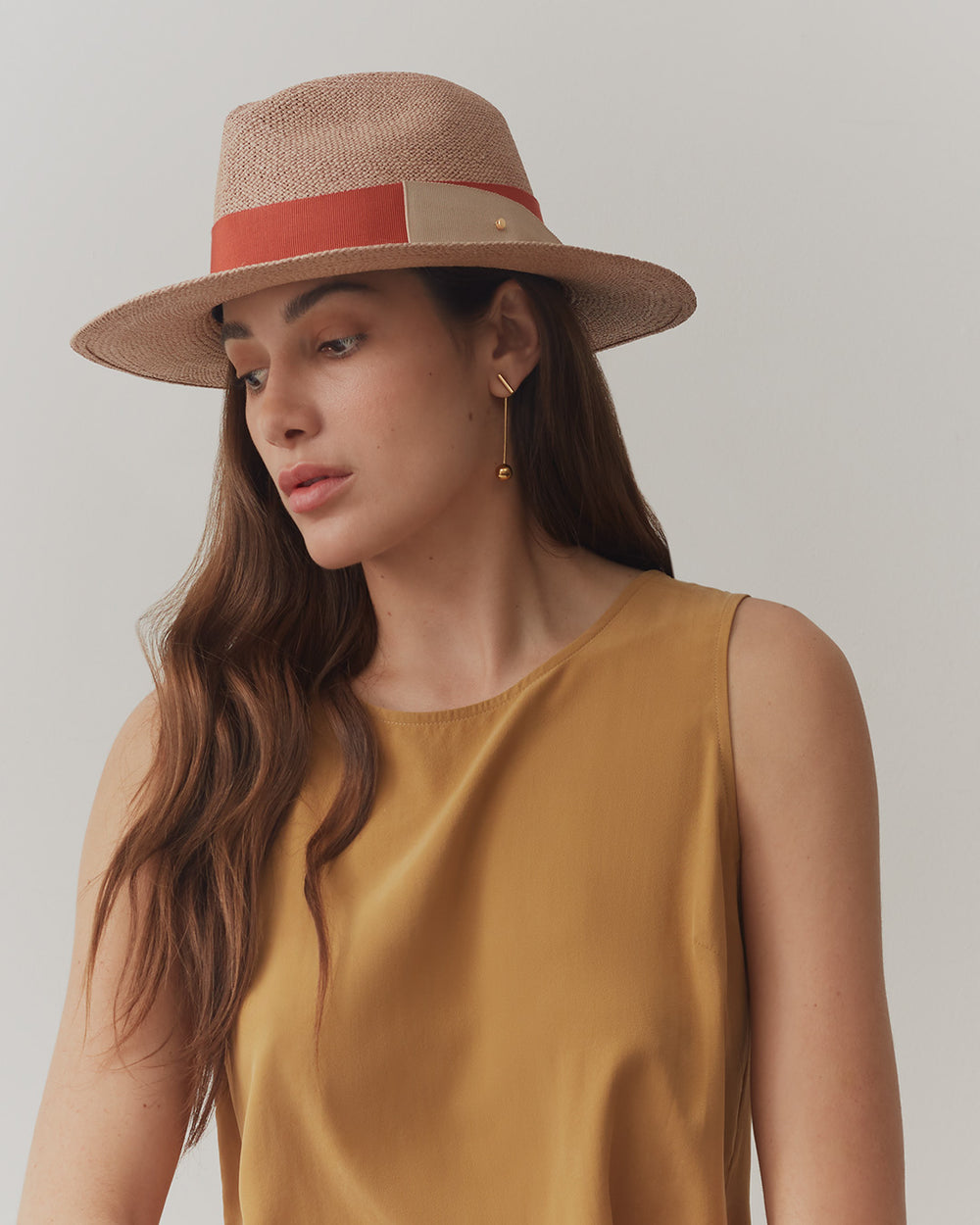 Woman wearing a hat and sleeveless top looking away.