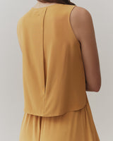 Person wearing a sleeveless top with a pleated back.