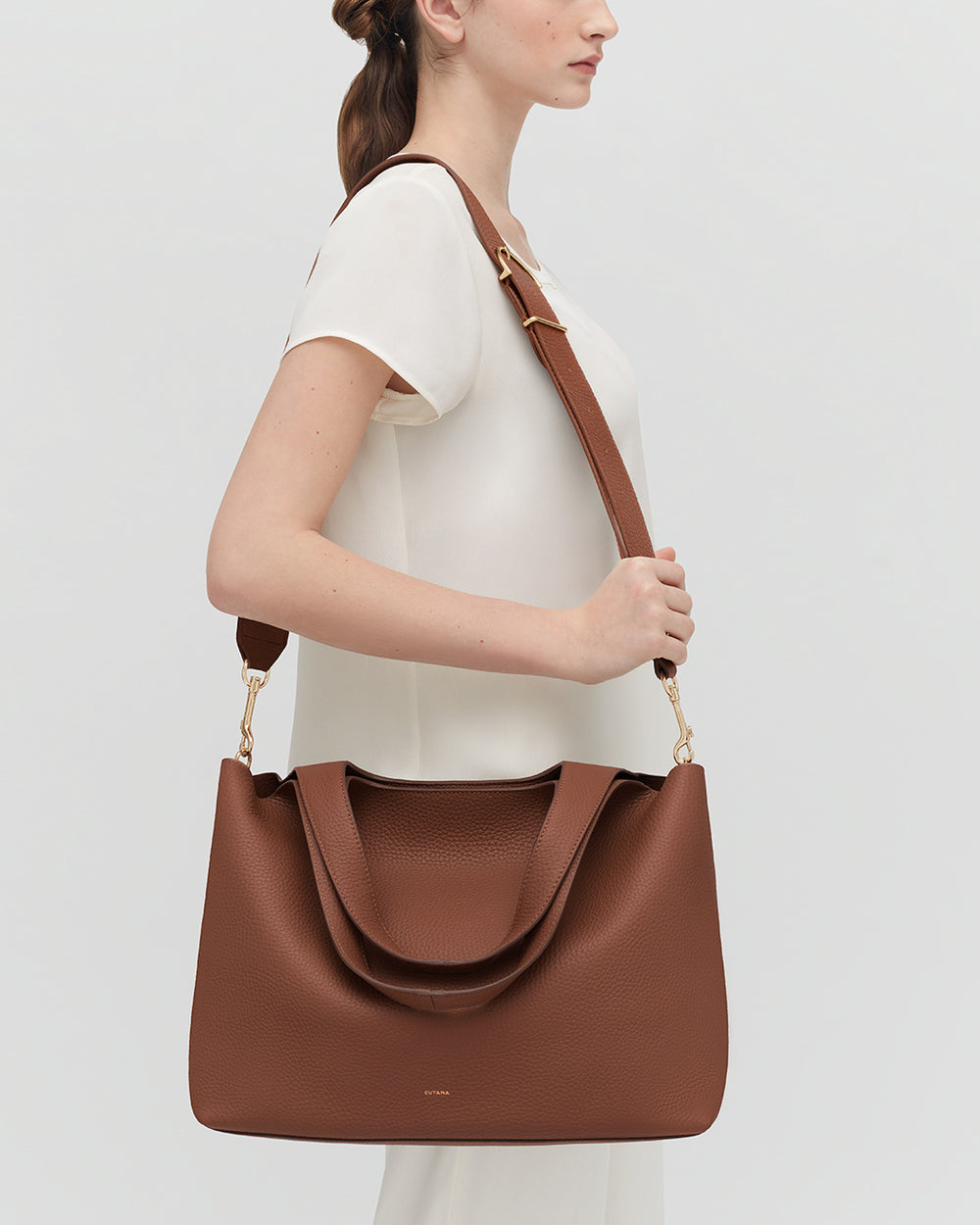 Person wearing a large handbag with a wide shoulder strap.