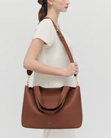Person wearing a large handbag with a wide shoulder strap.