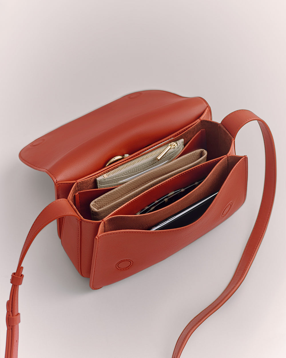 Open bag with multiple compartments holding a wallet and other small items