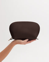 A hand holding a semi-circular pouch with a zipper.