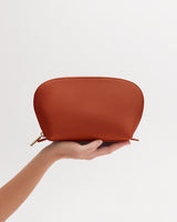 Person holding a small pouch against a plain background.