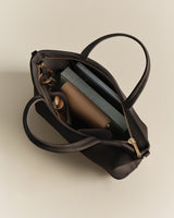 Open handbag with books, a wallet, and a small bottle inside