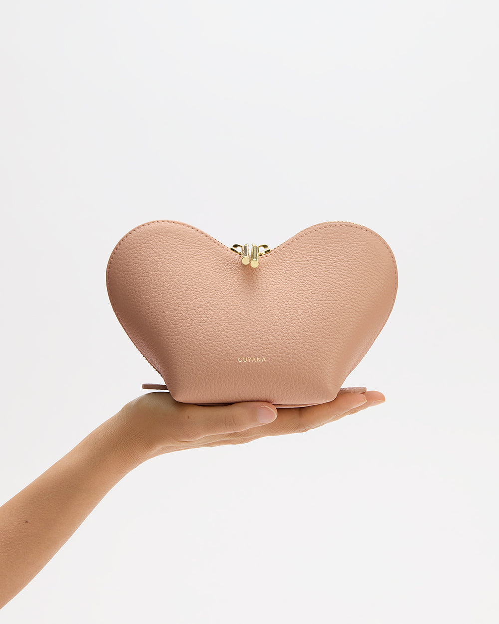 Person holding heart-shaped pouch against a plain background.