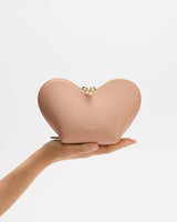 Person holding heart-shaped pouch against a plain background.