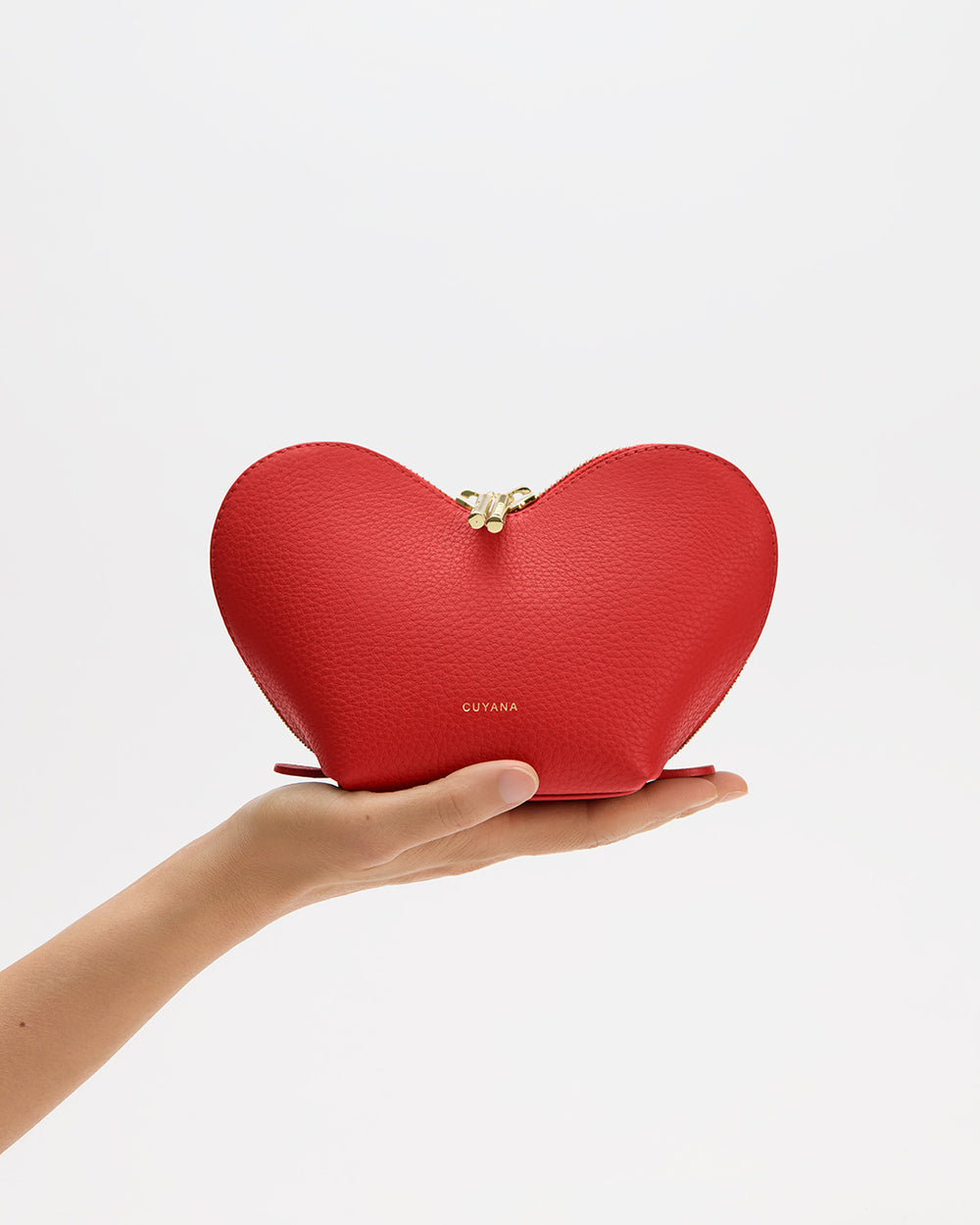 Heart-shaped pouch held in hand, zipper closure at top.