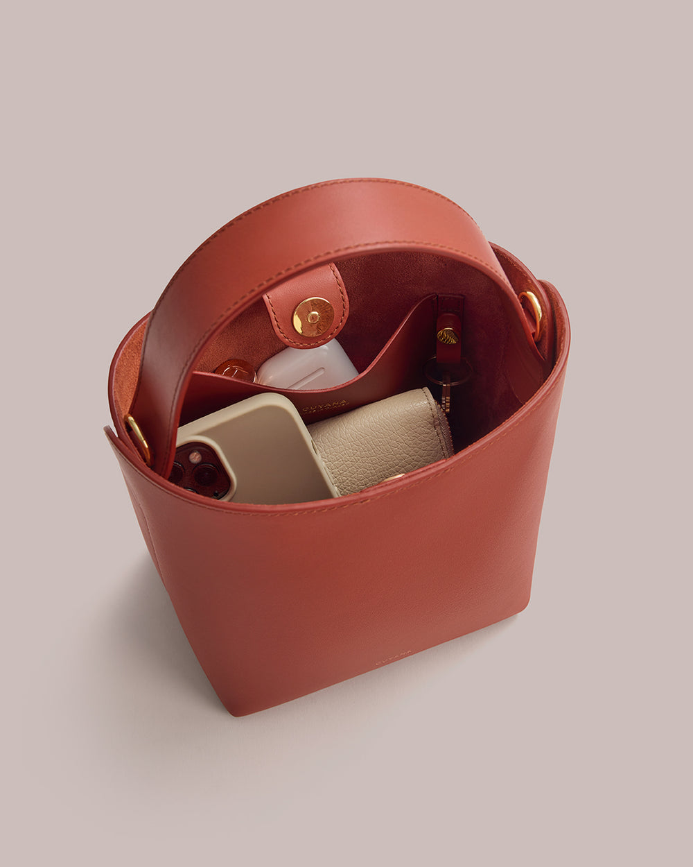 Open bucket bag with a phone, wallet, and water bottle inside.
