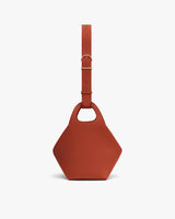 Hexagonal handbag with wide strap and round cut-out handle.