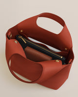Open handbag with a zipper pouch and other contents inside.