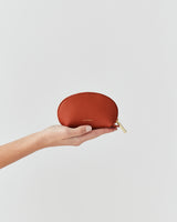 Hand holding a small leather pouch with a zipper.