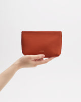 Hand holding a leather pouch against a plain background