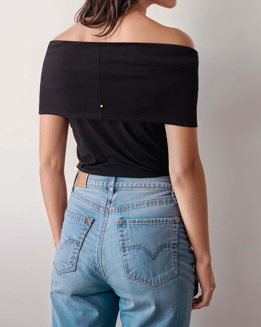 Person wearing off-shoulder top and jeans, facing away.