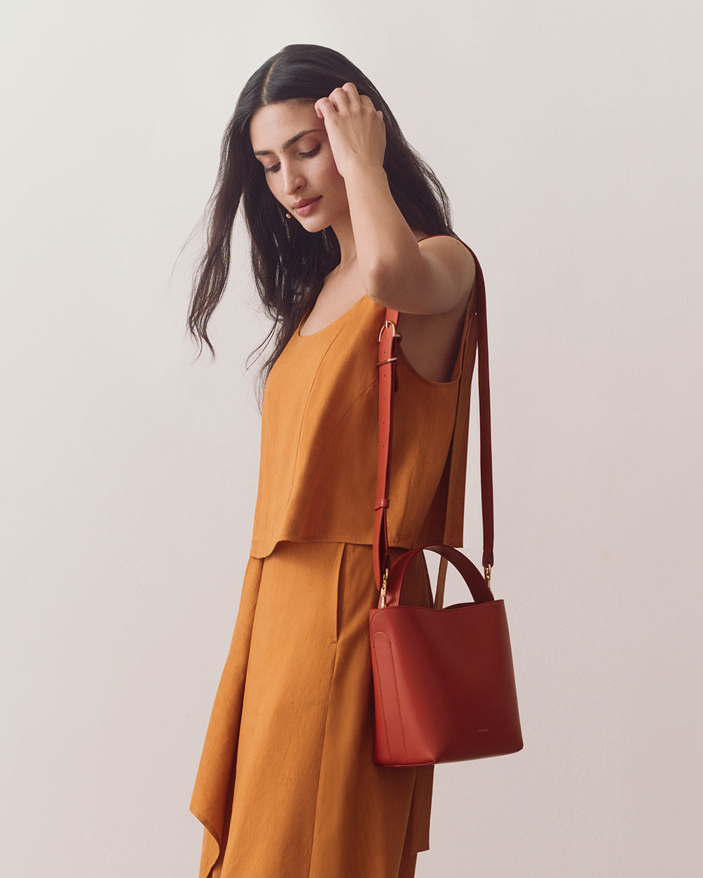 Person wearing sleeveless top and skirt with a shoulder bag