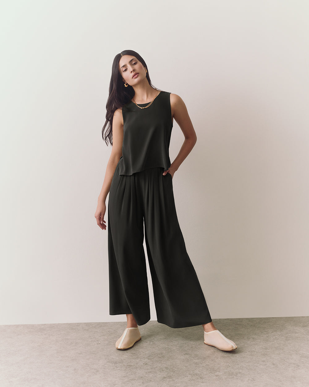 Person wearing sleeveless top and wide pants standing indoors