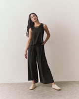 Person wearing sleeveless top and wide pants standing indoors