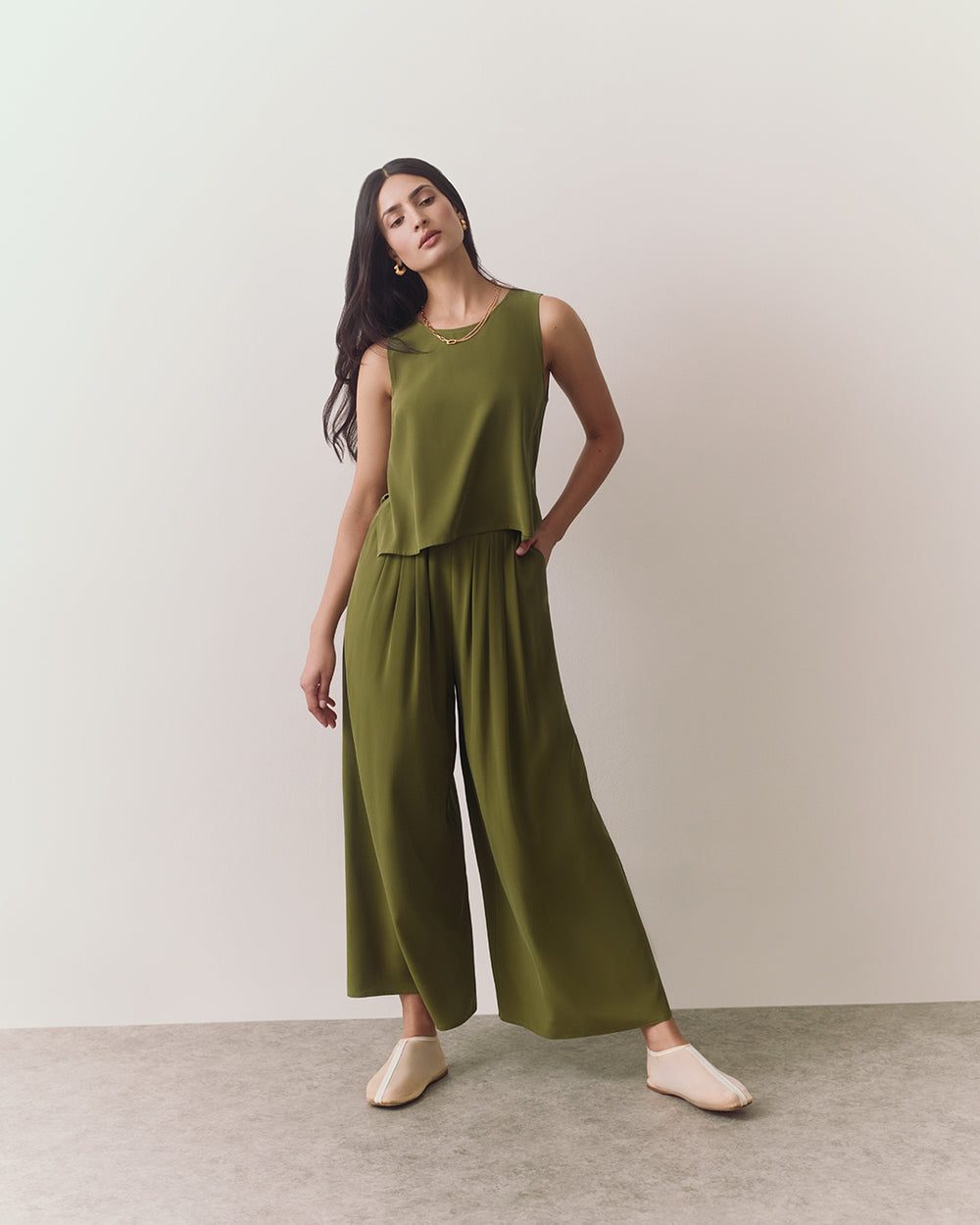 Person wearing a sleeveless top and wide-leg pants stands on a plain background.