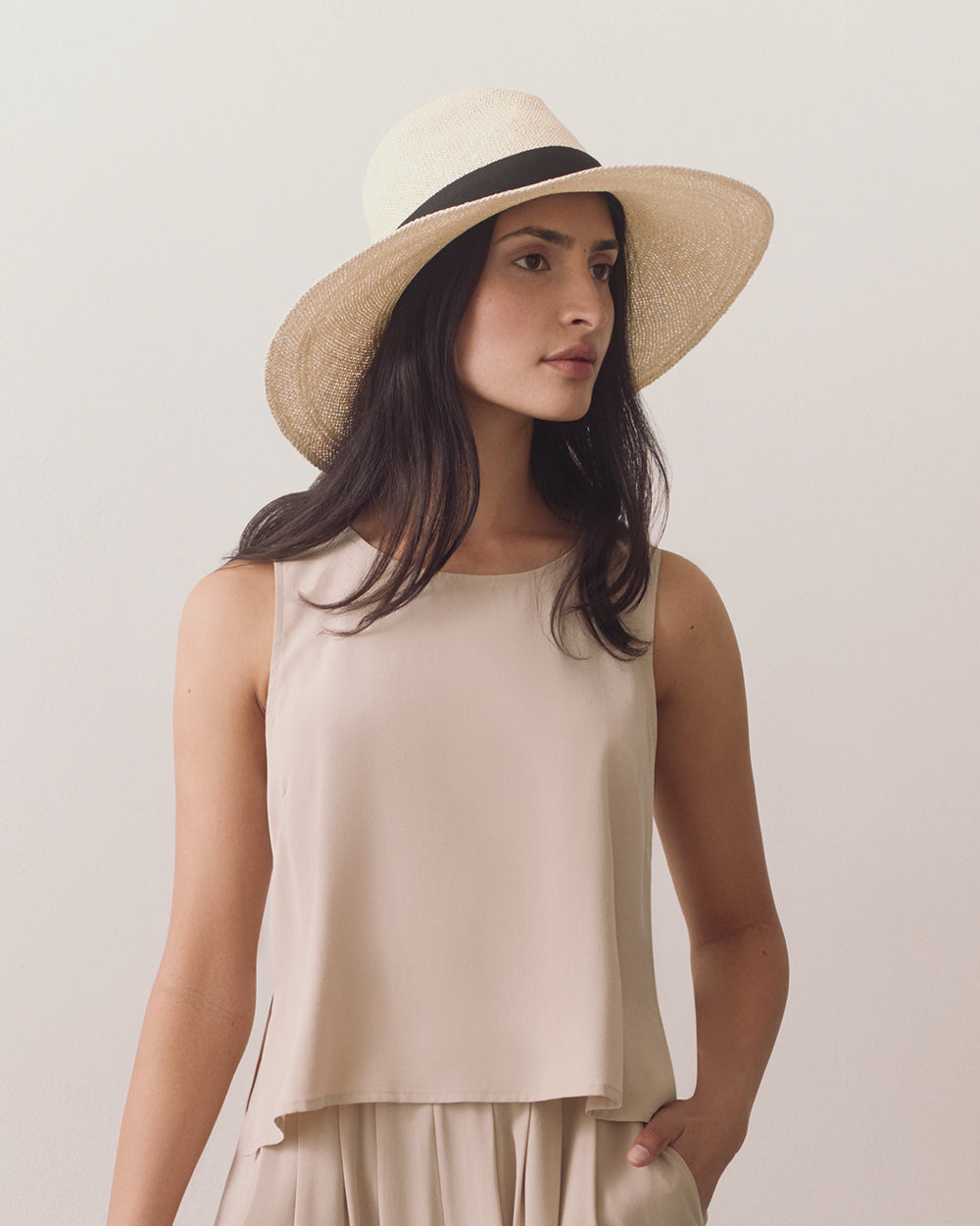 Person wearing a sleeveless top and a wide-brimmed hat.
