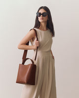 Woman wearing sleeveless dress with handbag over shoulder and sunglasses