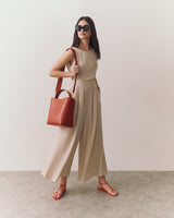Woman in  wide-leg pants with a sleeveless top wearing sunglasses and holding a handbag.