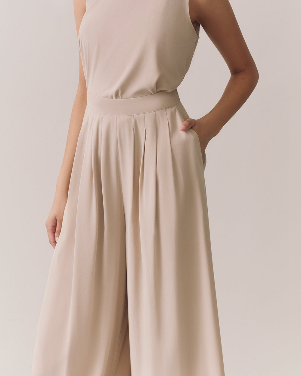 Person wearing a sleeveless top and wide-leg pants with hands in pockets