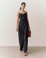 Person wearing a cami, wide leg pants, and a handbag, walking indoors.