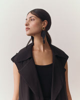 Person wearing a vest with large earrings looking to the side