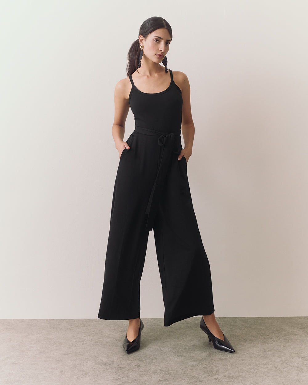 Person in a sleeveless jumpsuit standing in a neutral pose
