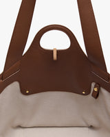 Open leather tote bag with a handle showing the interior fabric lining.