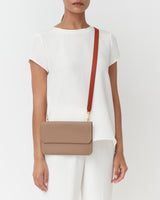 Person wearing a plain outfit with a shoulder bag.
