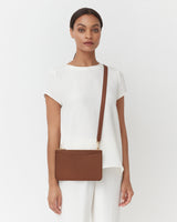 Person wearing a shirt and pants holding a clutch pouch.