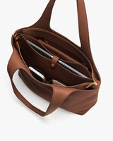 Open tote bag with a laptop, notebook, and small items inside.