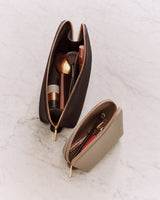 Two makeup bags with various cosmetics on a surface.