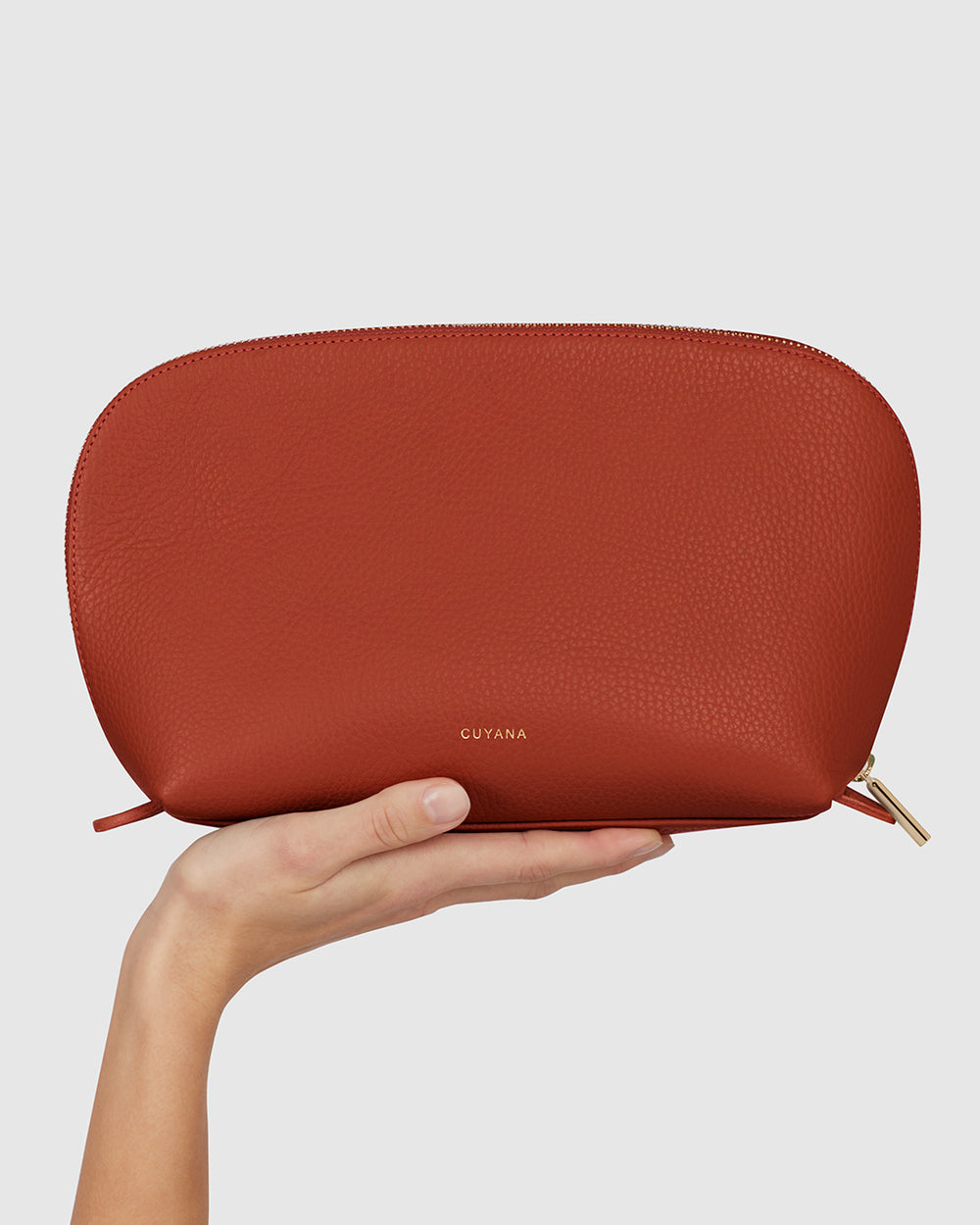 Hand holding a zippered leather pouch