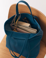 Open travel bag on a chair with books and folders inside.