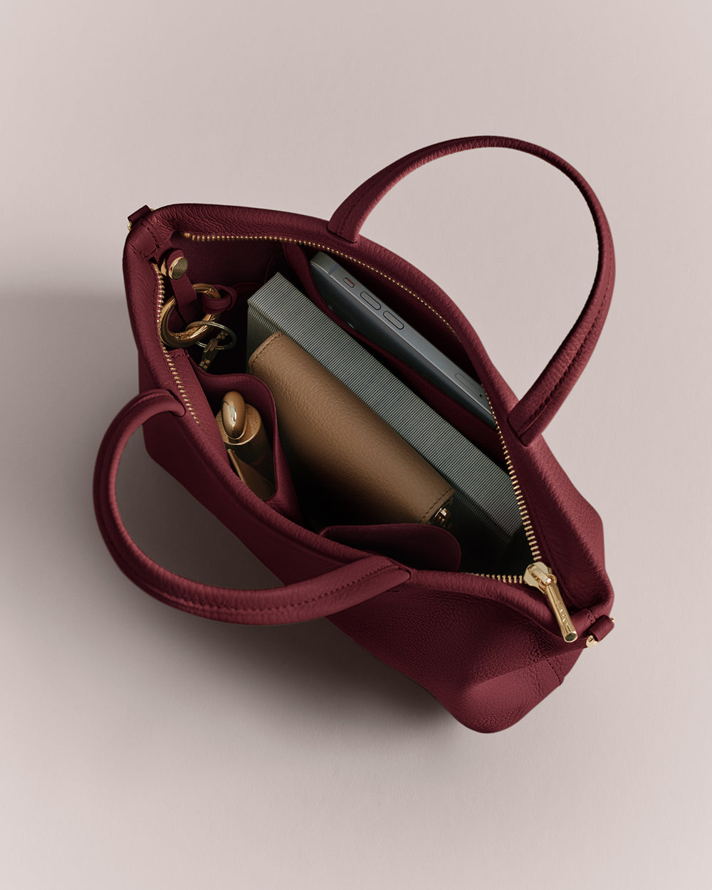 Open handbag with items inside including a wallet, book, and keys.