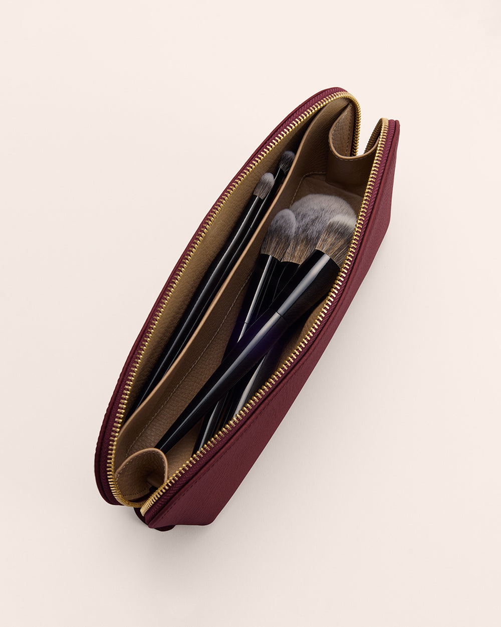 Open makeup bag with brushes inside shown from above.