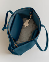 Open travel bag with a wallet, folded blanket, and keychain inside.