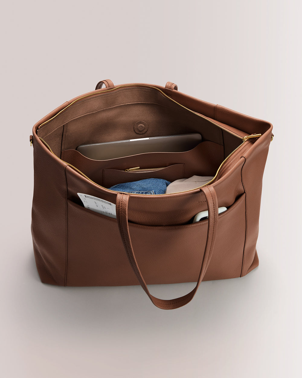 Open travel bag with visible interior pockets and packing items inside and outside.